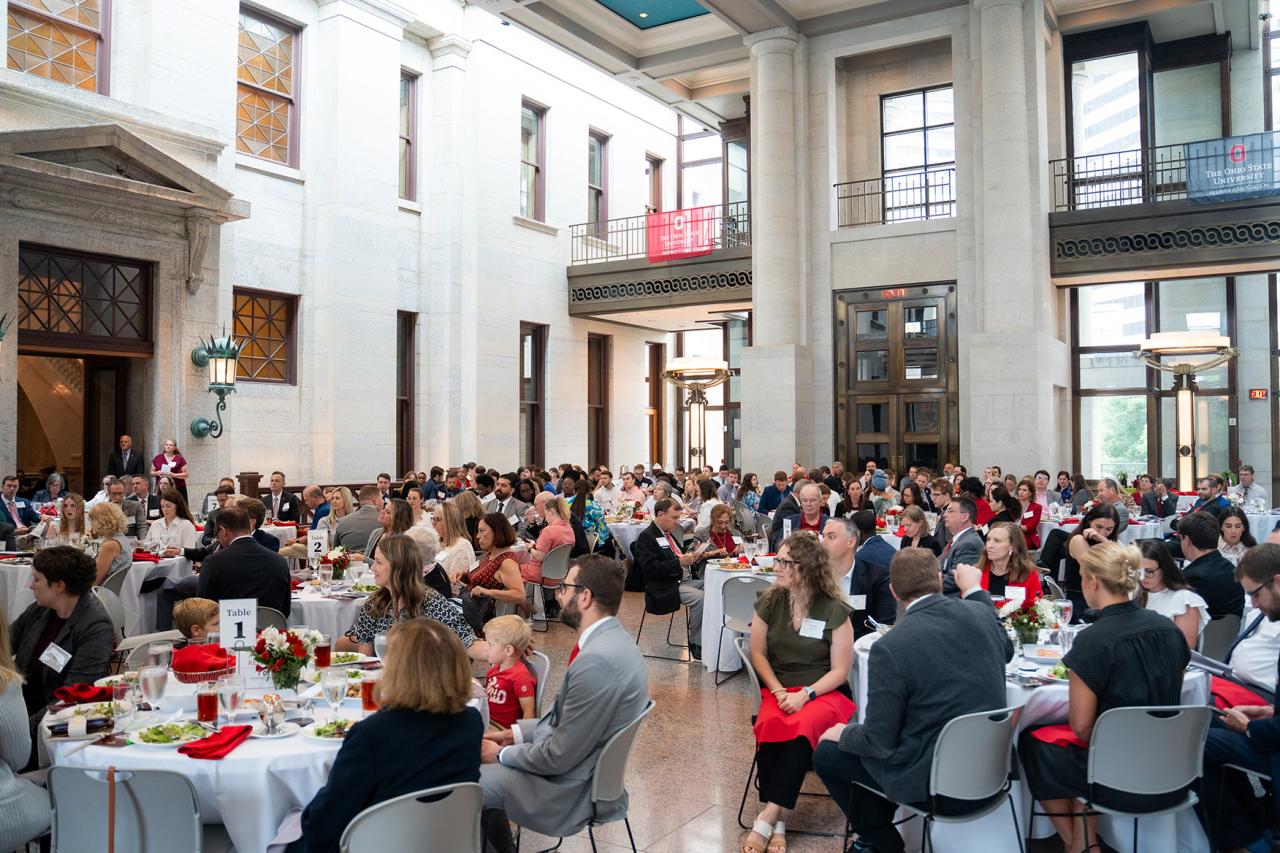 A large group of people seated at round tables in an event hall